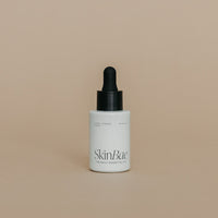 Skincare dropper bottle with 'SkinBar' branding on a beige background